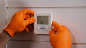 Technician placing cover on digital carrier thermostat