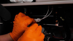 Man with orange gloves connecting wires